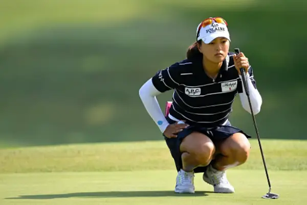 고진영 선수가 필드에서 골프채를 들고 앉아있는 모습